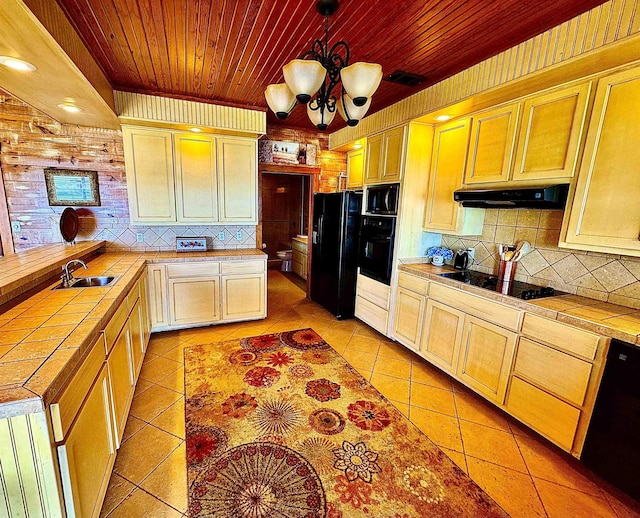 kitchen featuring backsplash, light tile patterned floors, black appliances, tile counters, and under cabinet range hood