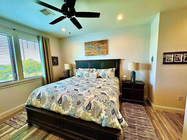 bedroom with baseboards, visible vents, and wood finished floors