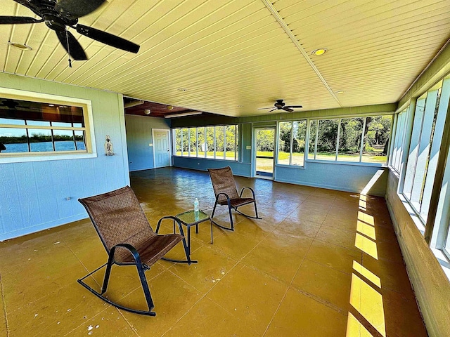 unfurnished sunroom featuring a ceiling fan and a wealth of natural light