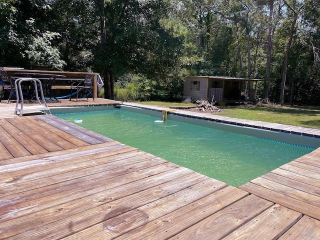 view of swimming pool with a deck, an outdoor structure, and a lawn