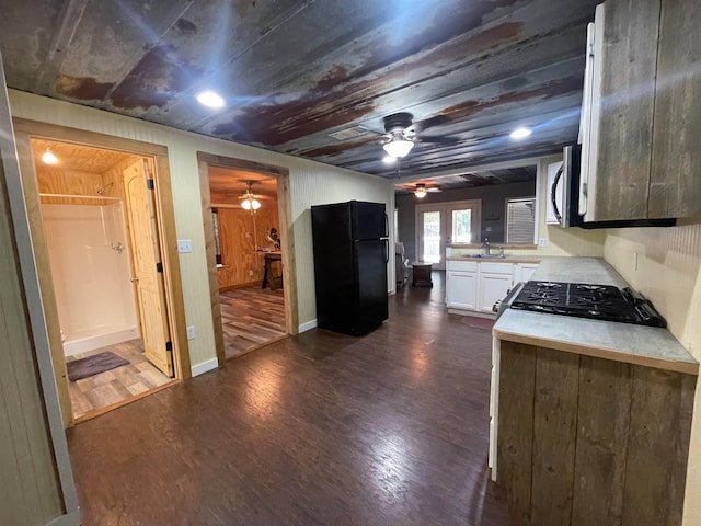 kitchen featuring range, black fridge, sink, dark hardwood / wood-style floors, and white cabinetry