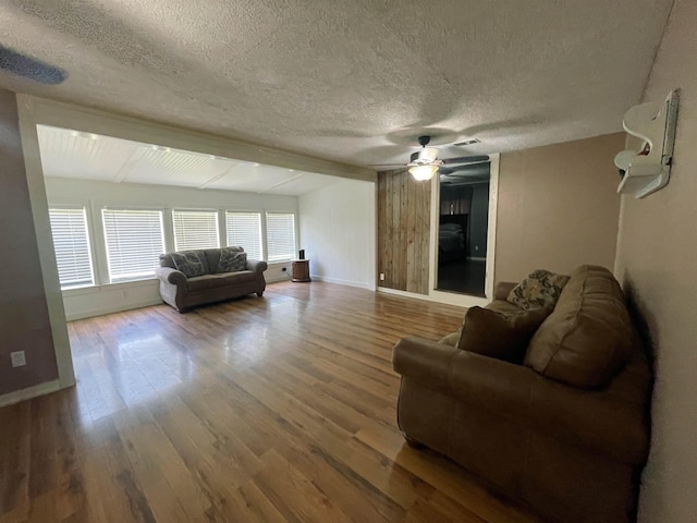 living room featuring ceiling fan, hardwood / wood-style floors, and a textured ceiling