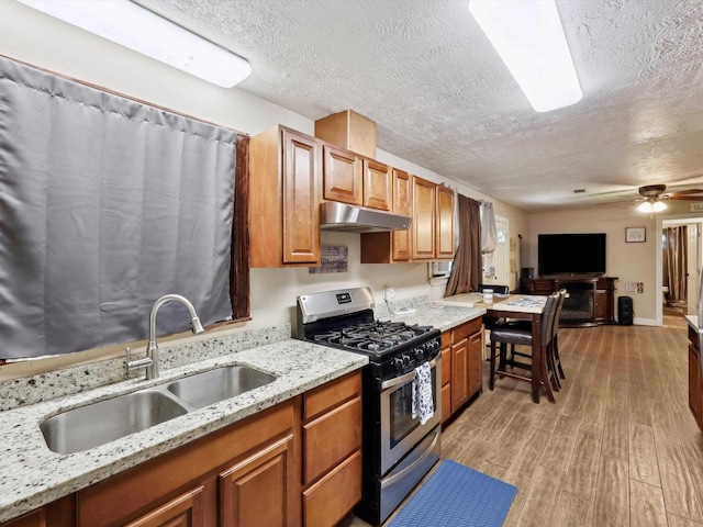 4015 42nd St, Port Arthur, TX 77642 - kitchen with gas stove, under cabinet range hood, light wood finished floors, a textured ceiling, and brown cabinets