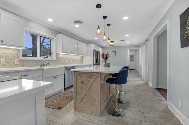 5855 Gladys Ave, Beaumont, TX 77706 - kitchen with appliances with stainless steel finishes, decorative backsplash, crown molding, a kitchen island, and recessed lighting
