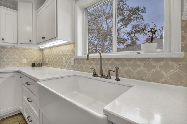 5855 Gladys Ave, Beaumont, TX 77706 - kitchen featuring a sink, light countertops, white cabinets, and backsplash