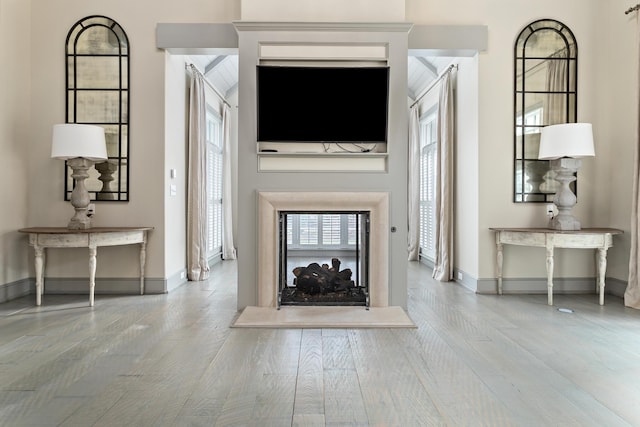 unfurnished living room with a multi sided fireplace and light hardwood / wood-style floors