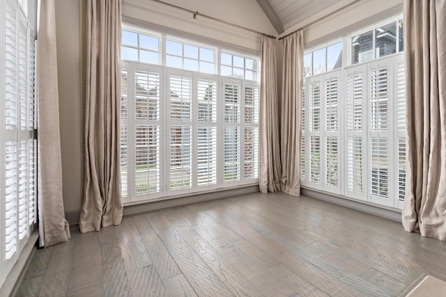 spare room featuring wood-type flooring, lofted ceiling, and plenty of natural light