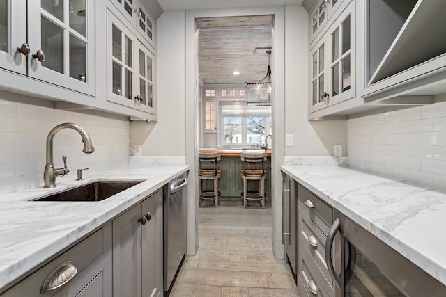 kitchen with gray cabinets, light stone countertops, and sink