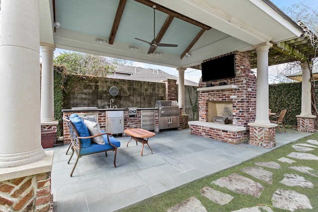 view of patio / terrace featuring sink, ceiling fan, an outdoor brick fireplace, a gazebo, and an outdoor kitchen