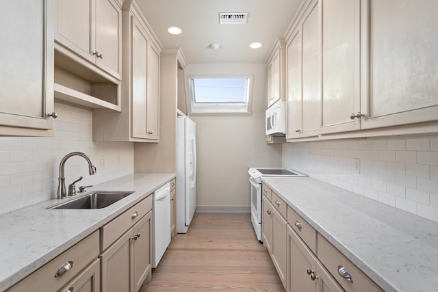 kitchen featuring sink, white appliances, light hardwood / wood-style flooring, tasteful backsplash, and light stone countertops