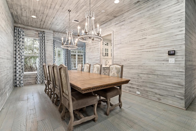 dining room with a notable chandelier, wood ceiling, wood walls, and hardwood / wood-style flooring