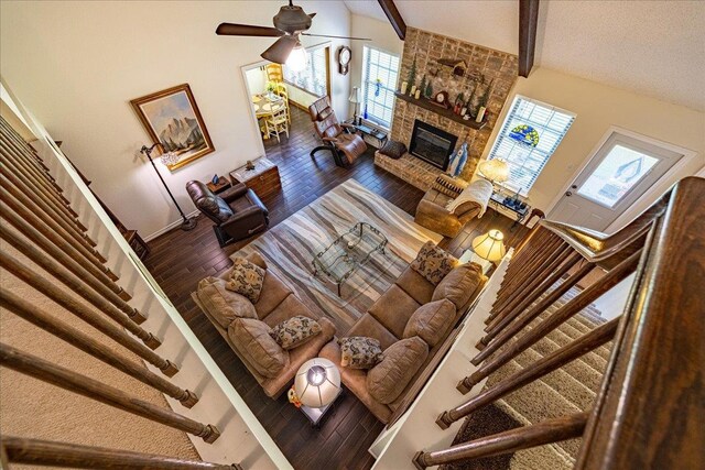 living room featuring dark hardwood / wood-style flooring, ceiling fan, beam ceiling, high vaulted ceiling, and a fireplace