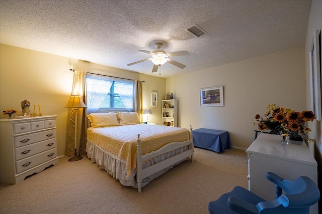 bedroom with a textured ceiling, light colored carpet, and ceiling fan