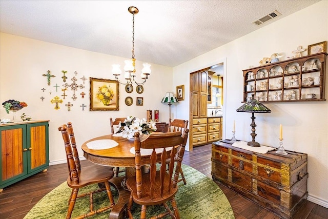 dining room with dark hardwood / wood-style flooring, a textured ceiling, and a chandelier