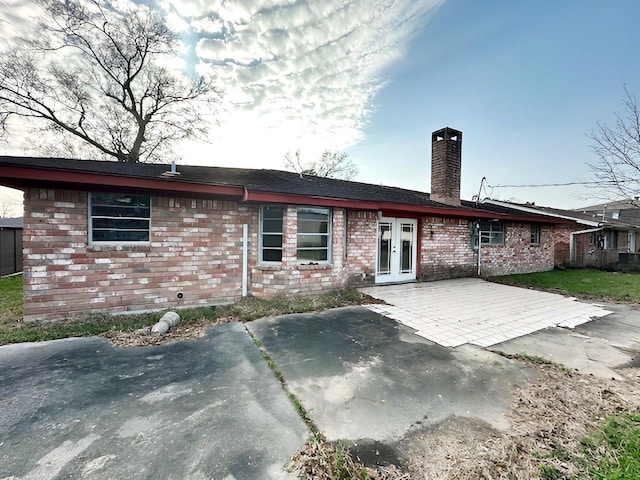 back of property featuring a patio, french doors, a chimney, and brick siding