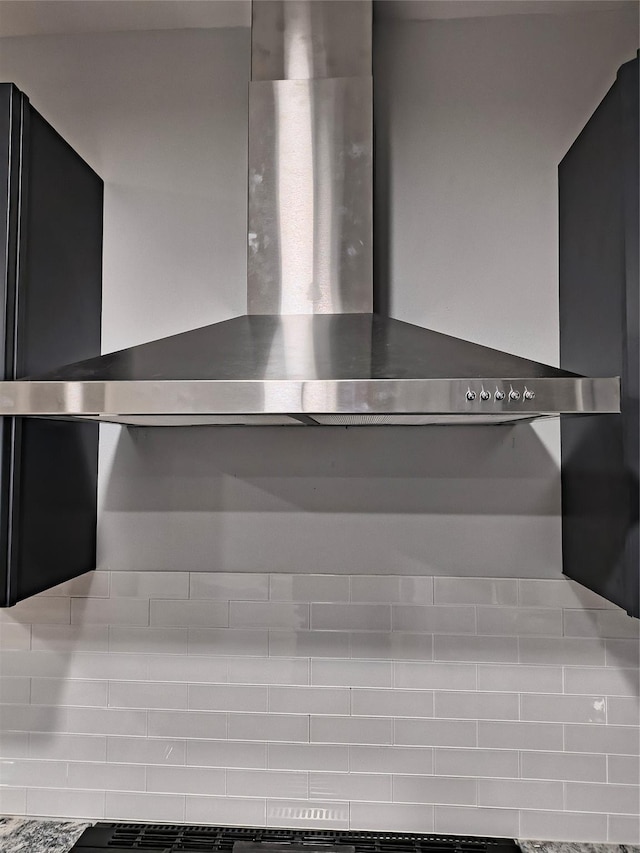 interior details featuring light stone countertops and wall chimney range hood