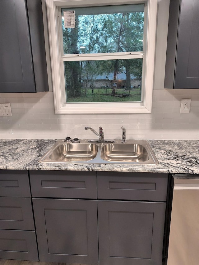 details featuring gray cabinets, decorative backsplash, and sink