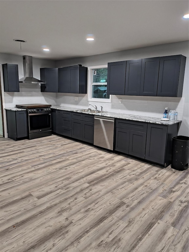850 Orange St, Vidor, TX 77662 - kitchen featuring wall chimney exhaust hood, stainless steel appliances, light stone counters, light hardwood / wood-style flooring, and backsplash