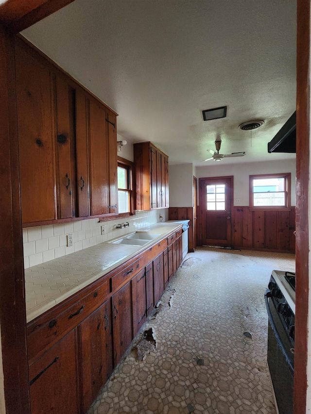 970 Peyton Dr, Beaumont, TX 77706 - kitchen with gas stove, plenty of natural light, ceiling fan, brown cabinets, and wainscoting
