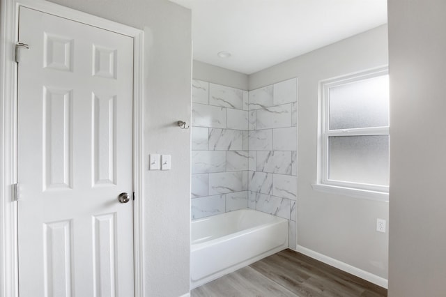 bathroom with hardwood / wood-style flooring and tiled shower / bath combo