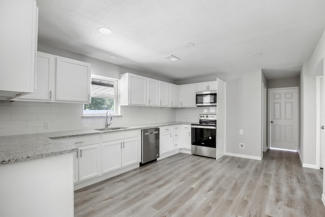 kitchen featuring white cabinetry, sink, stainless steel appliances, light stone counters, and decorative backsplash