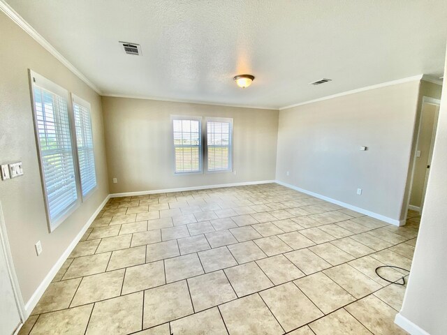 spare room with ornamental molding, plenty of natural light, and visible vents