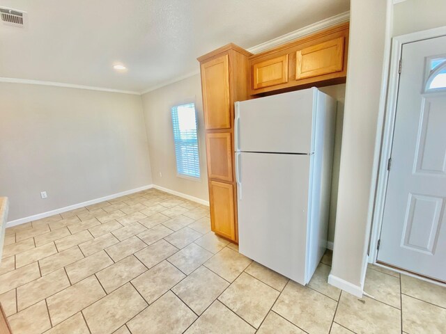 kitchen featuring light tile patterned floors, visible vents, ornamental molding, freestanding refrigerator, and baseboards