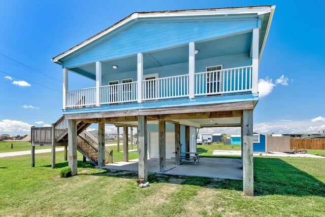 rear view of house with a patio, an attached garage, stairs, a lawn, and a carport