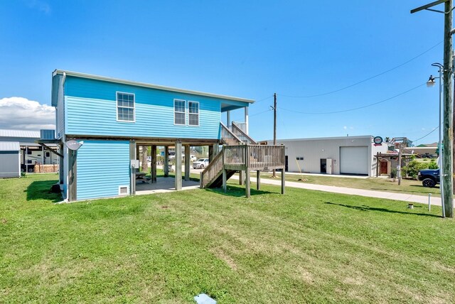 back of house featuring stairs, a carport, and a yard