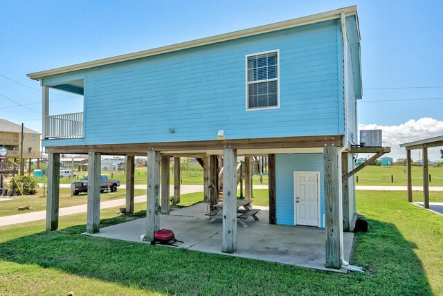 exterior space featuring a balcony, central AC, a lawn, and a carport