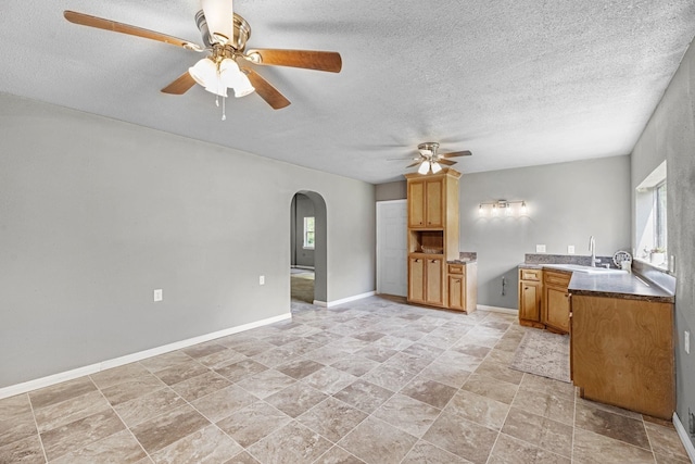 18425 Ramsey Rd, Crosby, TX 77532 - kitchen featuring a ceiling fan, arched walkways, a textured ceiling, and brown cabinets