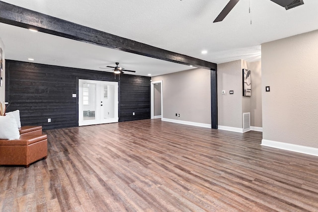 unfurnished living room featuring ceiling fan, beam ceiling, and wood-type flooring