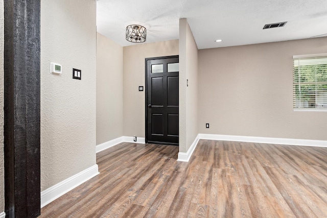 entryway featuring hardwood / wood-style flooring, a textured ceiling, and an inviting chandelier