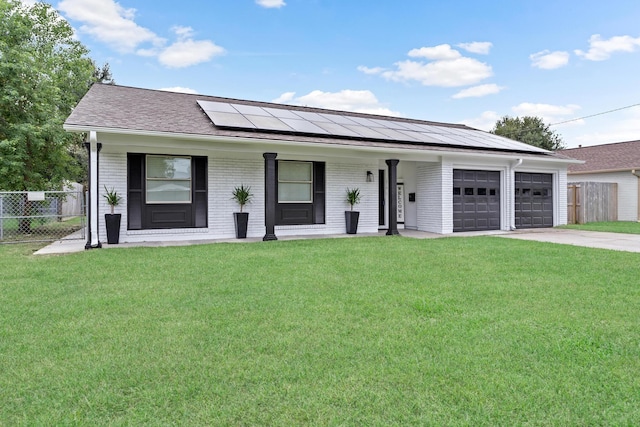 single story home with solar panels, a porch, a garage, and a front yard