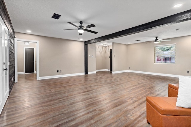 unfurnished living room featuring beam ceiling, ceiling fan, dark wood-type flooring, and a textured ceiling