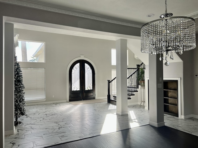 entrance foyer featuring a notable chandelier, plenty of natural light, ornamental molding, and french doors