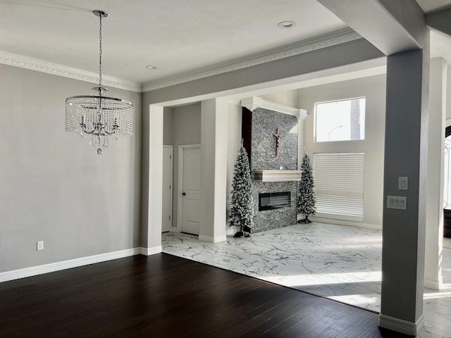 unfurnished living room featuring crown molding, wood-type flooring, a fireplace, and a chandelier