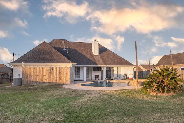 back of property with central AC unit, a fenced in pool, a patio, and a lawn