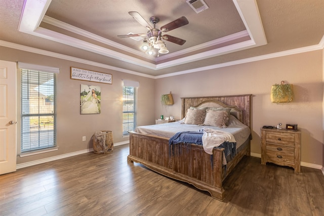 bedroom featuring ceiling fan, ornamental molding, multiple windows, and a tray ceiling