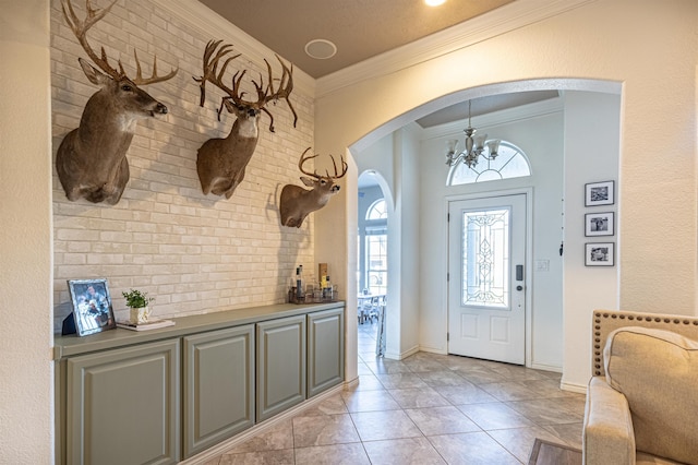 entrance foyer with light tile patterned floors, a chandelier, and ornamental molding