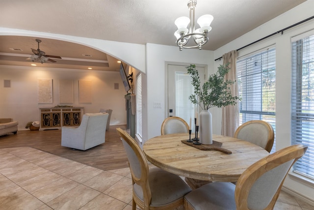 tiled dining space with ceiling fan with notable chandelier and plenty of natural light