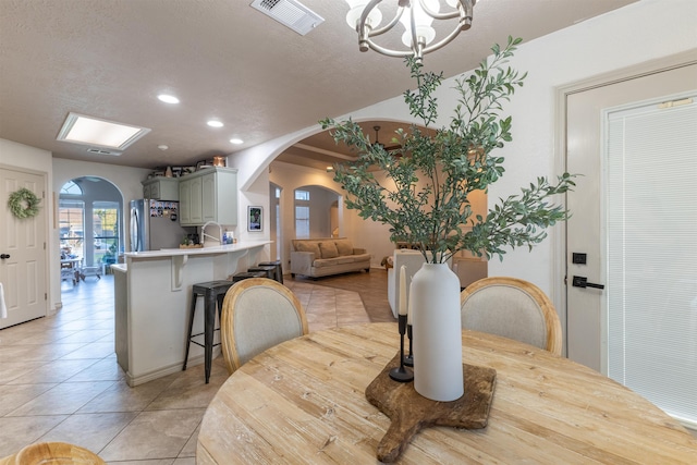 dining space with sink, light tile patterned floors, a textured ceiling, and a chandelier