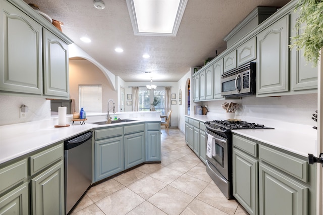 kitchen featuring a textured ceiling, stainless steel appliances, sink, light tile patterned floors, and a notable chandelier