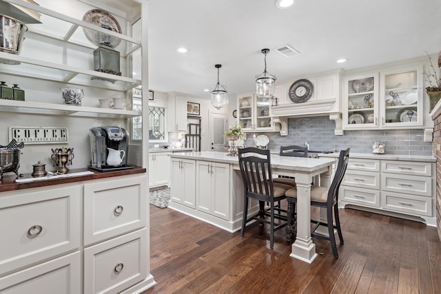 kitchen featuring a breakfast bar, white cabinetry, tasteful backsplash, decorative light fixtures, and a kitchen island