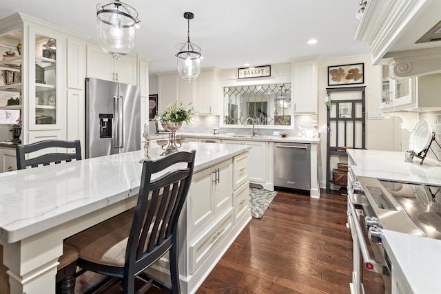 kitchen with sink, white cabinets, pendant lighting, stainless steel appliances, and backsplash