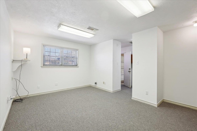 basement with carpet flooring, visible vents, a textured ceiling, and baseboards