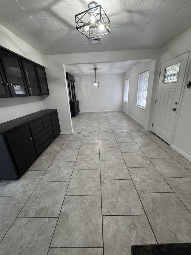 unfurnished dining area featuring light tile patterned flooring, visible vents, and baseboards