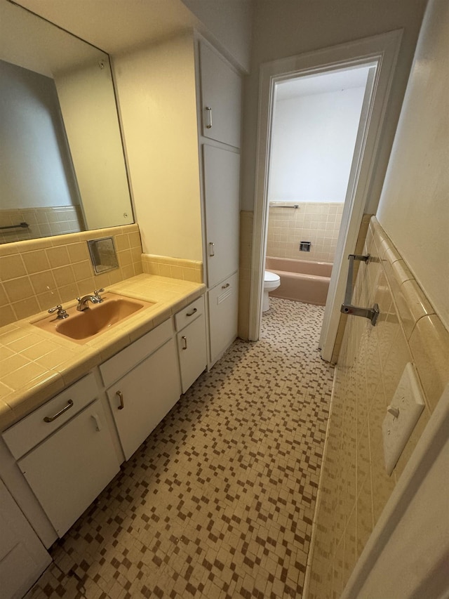 bathroom with a tub to relax in, toilet, vanity, and backsplash