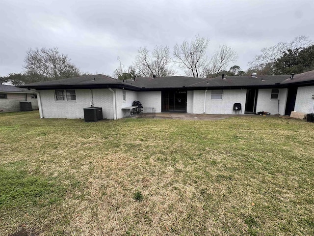 rear view of property with central AC and a lawn