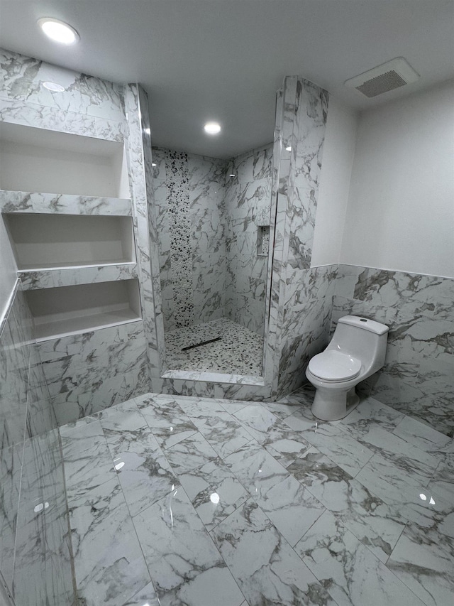 bathroom with a tile shower and toilet